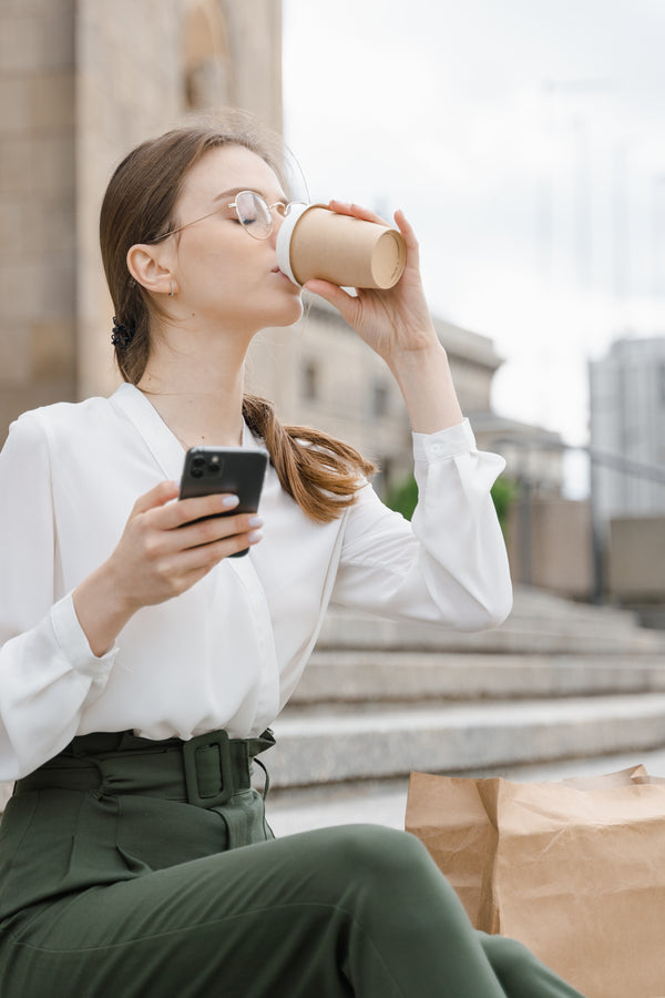 Woman drinking coffee in paper, recyclable cup